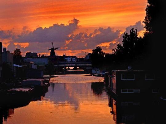 Saharazand kleurt Nederlandse hemel rood en oranje / Foto: "Windmill in Amsterdam Oost" door David Evers