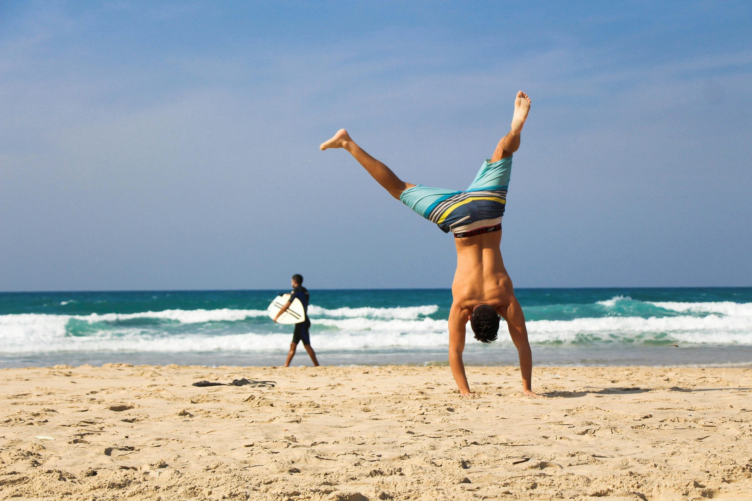 man doet handstand op strand
