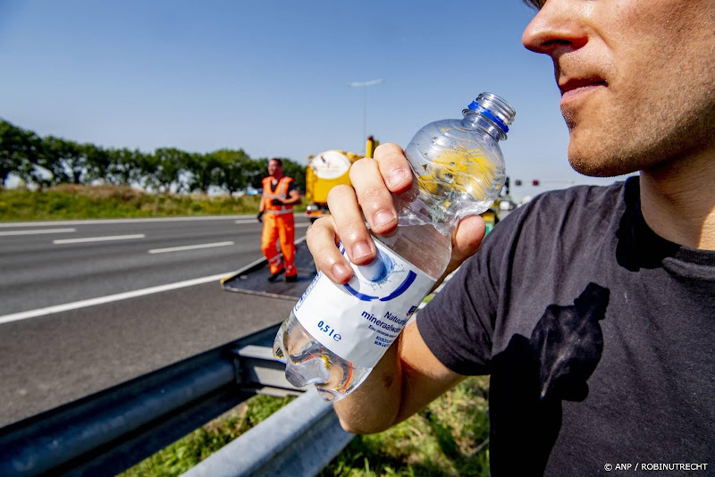 iemand achter vangrail met flesje water