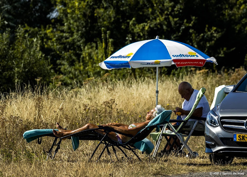 vrouw in de zon en man onder parasol