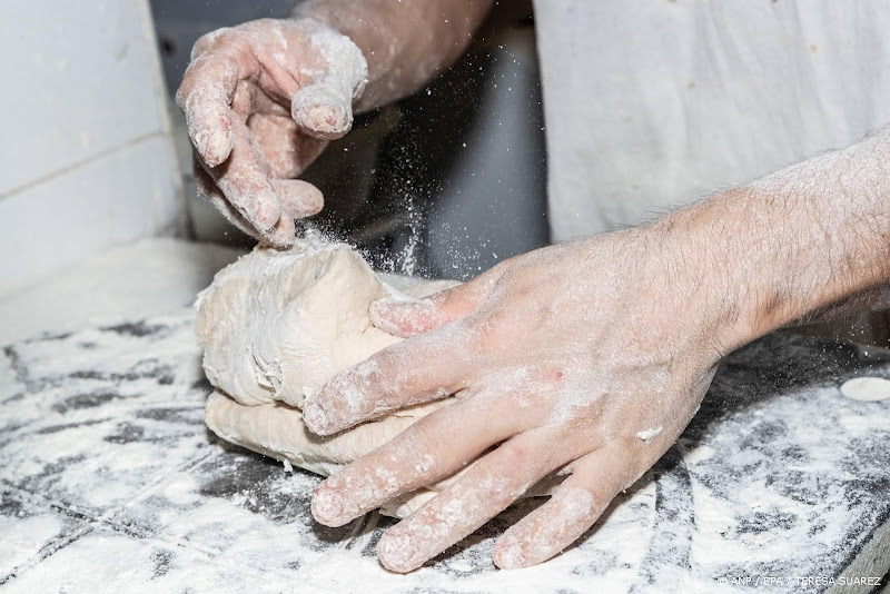 iemand met meel bestuifde handen die bezig is met een deeg