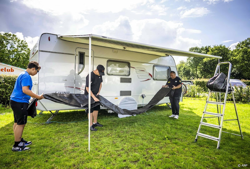 twee jongens en man vouwen grondzeil caravan op