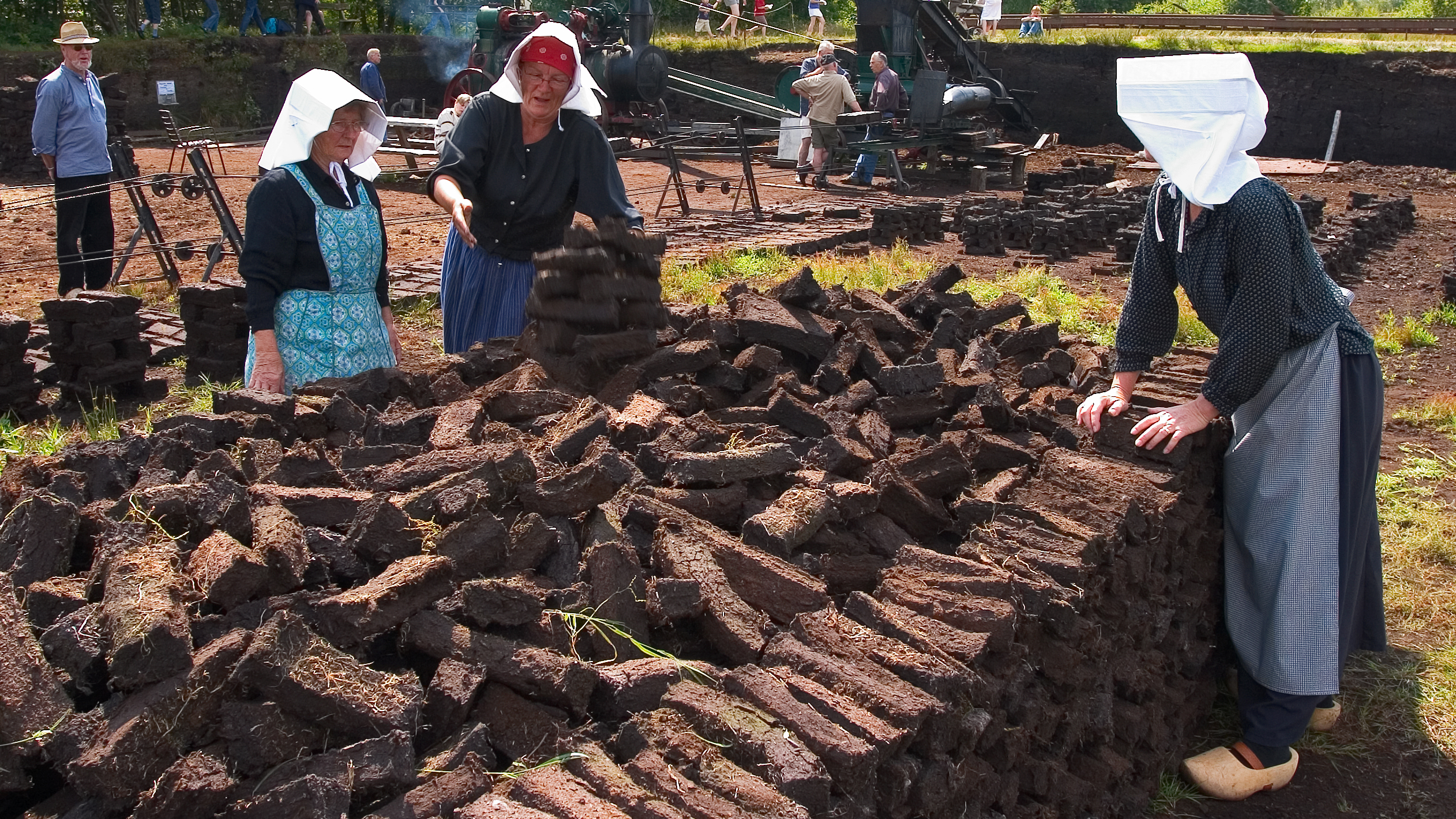 drie vrouwen in traditionele klederdracht bij turf